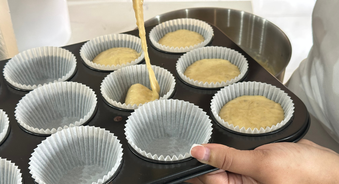 Muffin batter being poured into paper liners