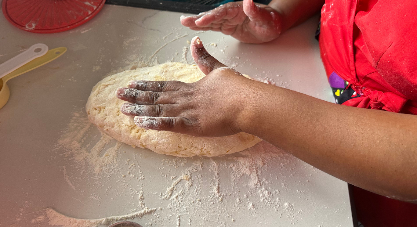 Scone dough being kneaded by hand on a floured board